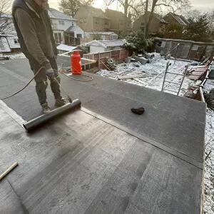 A man on a flat roof with a vacuum.
