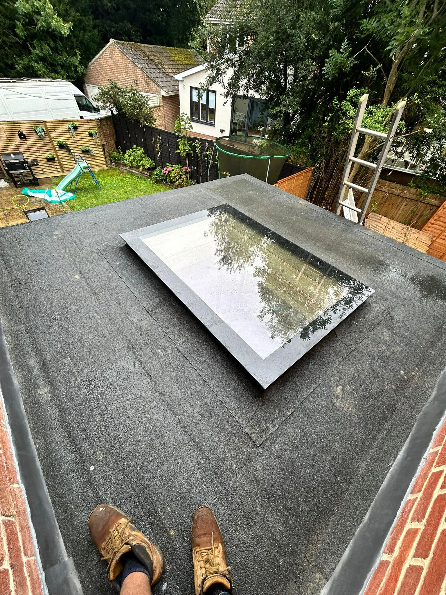 A person standing on a flat roof with their feet on the ground.