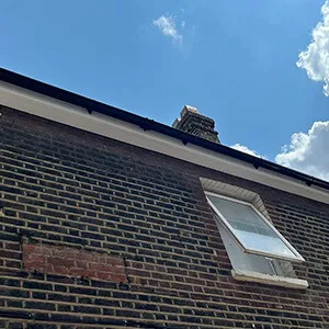 A brick building with a window and a sky background.